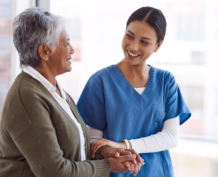 A health care worker holds the arm of a woman while she walks